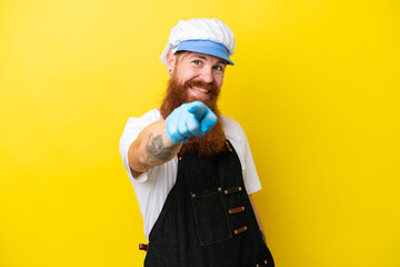 Wall Mural - Fishmonger wearing an apron isolated on yellow background points finger at you with a confident expression