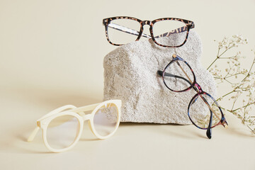 Wall Mural - several different trebdy eye glasses with fashion frames and concrete podium on beige background