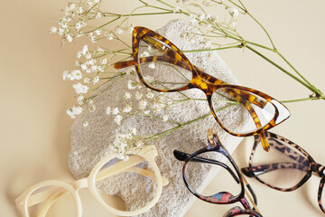 Sticker - several different trebdy eye glasses with fashion frames and concrete podium on beige background