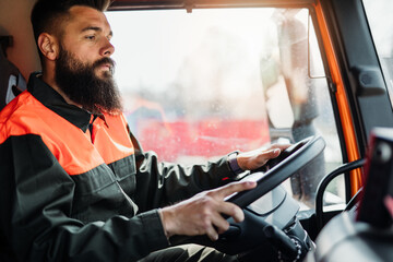 Wall Mural - Young garbage removal worker driving a waste truck