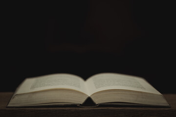 Image of an antique book open on a wooden table with vintage dark tone style.