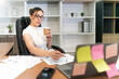 © tai - relax business beautiful asian woman work. professional woman sitting video call meeting with beverage in hand. calm glasses female employee talking online with business team worker holding coffee
