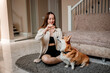 © bondvit - Attractive girl hug and play with corgi dog at home. Welsh Corgi Pembroke with his owner woman on the floor at living room