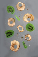 Wall Mural - apple fritters and slices of dried kiwi levitating against gray background