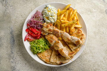 Wall Mural - souvlaki with chicken and pita on white plate, Greek cuisine top view on stone table