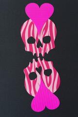 Wall Mural - two skull heads with stripe patterns and hot pink hearts on forehead on black paper