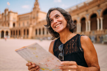 Wall Mural - Elderly woman at the map to decide what to visit in the city. Senior woman traveling in a city in Europe.