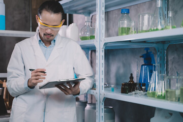 Wall Mural - research man is standing and making notes on a pen in his notebook in a laboratory.