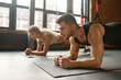 Man and woman standing in plank training at sport club gym