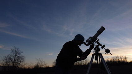 Wall Mural - silhouette of a man, telescope and countryside under evening skies.