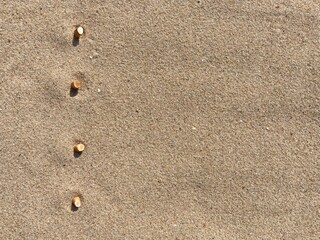 Aufkleber - Four cigarette butts arranged as bullet points in sand on beach