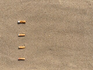 Aufkleber - Four cigarette butts arranged as bullet points in sand on beach