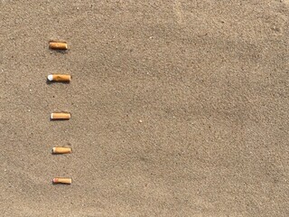 Aufkleber - five cigarette butts arranged as bullet points in sand on beach