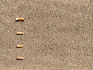 Aufkleber - Four cigarette butts arranged as bullet points in sand on beach