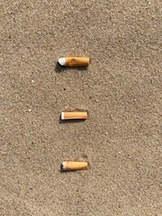 Aufkleber - three cigarette butts arranged as bullet points in sand on beach