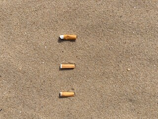 Aufkleber - three cigarette butts arranged as bullet points in sand on beach