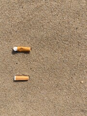 Aufkleber - two cigarette butts arranged as bullet points in sand on beach