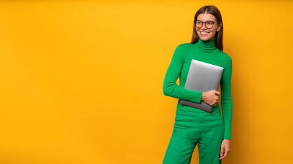 Wall Mural - Portrait of woman hr specialist holding laptop on yellow banner background going to interview