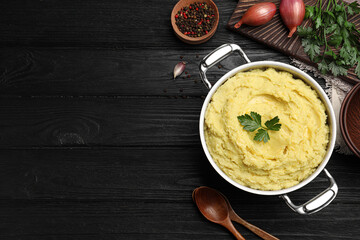 Wall Mural - Pot of tasty mashed potatoes with parsley on black wooden table, flat lay. Space for text