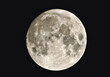 full moon shining with reflected light on a black background, visible craters, darker spots