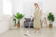 Lifestyle in living room concept, Young Asian woman using vacuum cleaner to cleaning the floor