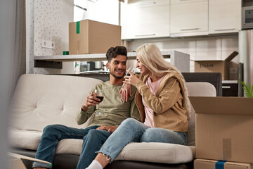 Wall Mural - Happy couple toasting wine from glasses on sofa