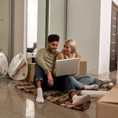 Wall Mural - Couple using laptop on blanket on floor with boxes