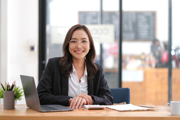 Portrait of smiling beautiful business asian woman with working in modern office desk using laptop computer, Business people employee freelance online marketing e-commerce telemarketing concept.