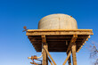 © Austockphoto - Looking up underneath a high tank stand with a rusting water tank on top and blue sky behind