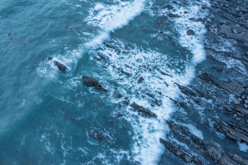 Wall Mural - Aerial drone landscape bird's eye view of vibrant sunset over Welcombe Mouth Beach in Devon England with waves crashing on rocks