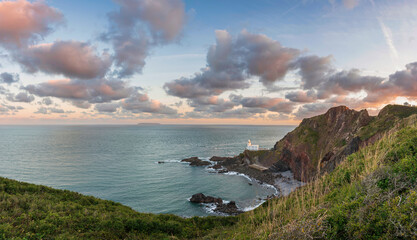 Wall Mural - Lovely sunrise landscape image of Devon coastline in England with stunning golden hour light on the land and sky