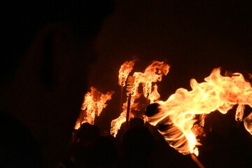 Wall Mural - People entering a cave at night with flaming torches