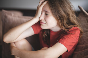 Wall Mural - Sad thoughtful teen girl sits on couch