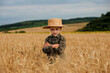 © volody10 - A smiling little farmer boy in a plaid shirt and straw hat poses for a photo in a wheat field. Heir of farmers