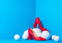 Stylish Fashion Female Red High-heeled Shoes Are Placed In A Cube With A Blue Solid Background And White Balls Around That Resemble Snowballs.