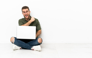 Canvas Print - Young man sitting on the floor celebrating a victory