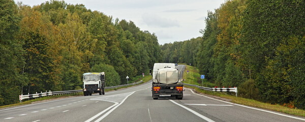 Wall Mural - Barrel truck transportate a liquid food goods on suburban highway road in forest at autumn day , back  view