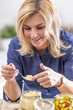 © weyo - Mid-aged blonde woman tastes crushed horseraddish from a glass jar