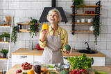 Fototapeta  - Attractive senior woman with grey hair cooking healthy food on her kitchen at home. Mature female preparing fresh vegetarian salad with organic ingredients from the market: tomato, cucumber, pepper