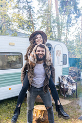 Wall Mural - Young beautiful loving couple travelling across country in the van. Millennial man and woman in a travel camper. Cozy atmosphere, vacations vibe. Playing guitar, drinking tea, taking selfie photo