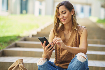 Middle aged using her smartphone with a pen or stylus, outdoor.
