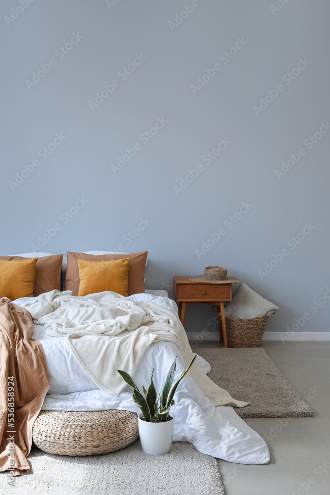 Interior of modern room with big bed, table and pouf