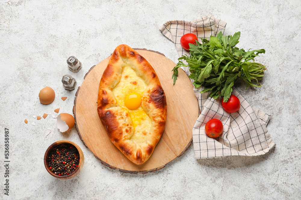 Composition with tasty Ajarian khachapuri, spices, tomatoes and arugula on light background