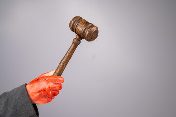Fototapeta a female judge holds a gavel in a bloody hand on a white background. copy space. 