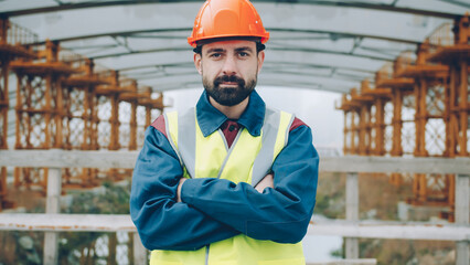 Ambitious engineer crossing arms standing in industrial area alone and looking at camera. Job abd specialists concept.