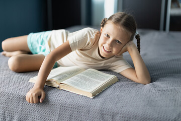 Wall Mural - Girl child reads a book in the room