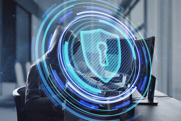 Poster - Side view of hacker at desktop using laptop with glowing shield hologram on blurry office interior background. Secure, data theft, malware, safety and web protection concept. Double exposure.