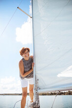 Cheerful Senior Woman Enjoying Vacation Standing Near Mast On Sailboat