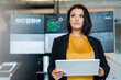© Westend61 - Thoughtful businesswoman holding tablet PC in front of computer monitors in industry