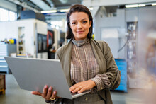 Smiling Businesswoman Holding Laptop In Industry